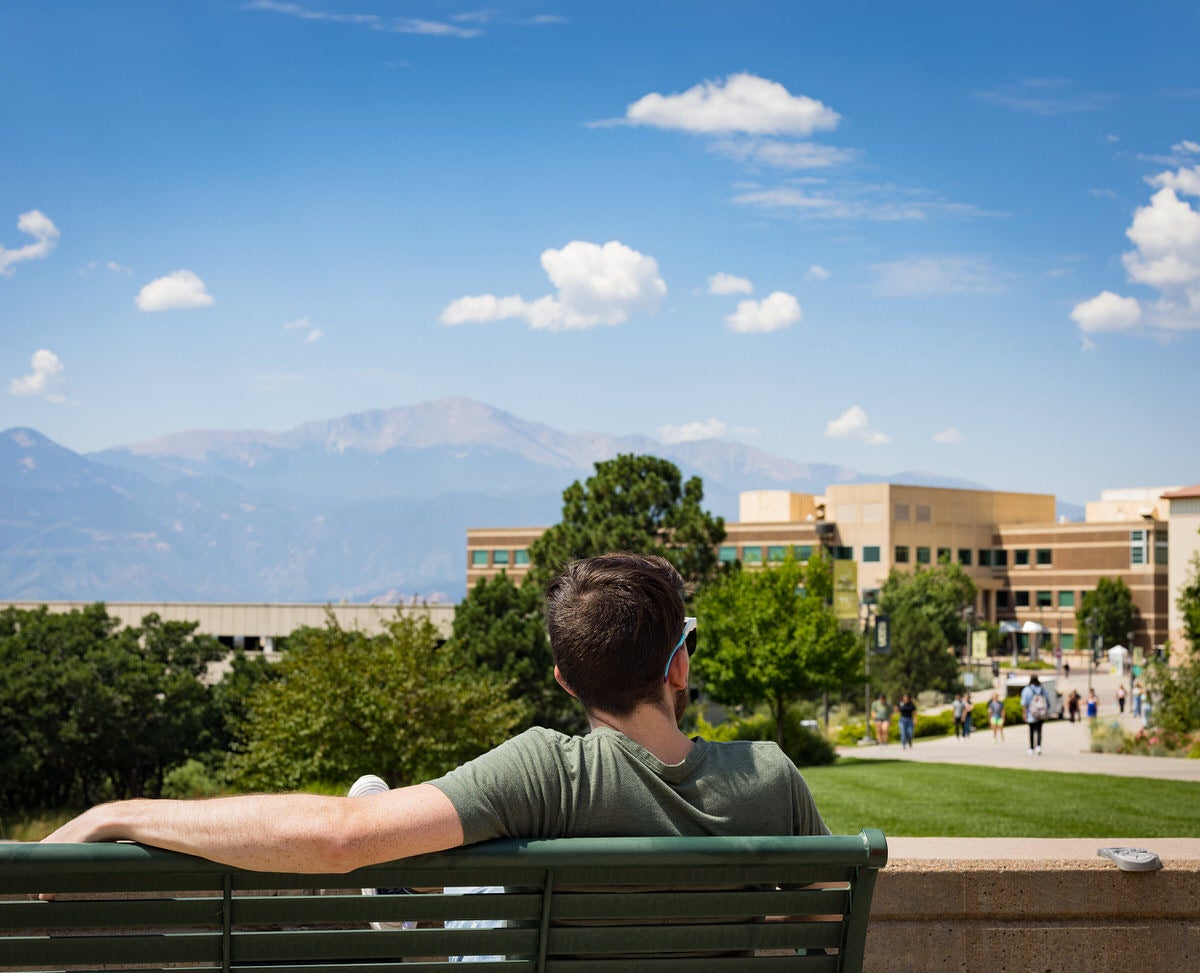 A man on a bench looking at UCCS campus