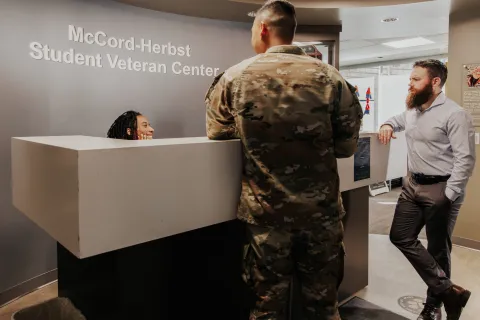 military student talking to staff members at the front desk of the Veteran Center